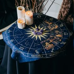 two candles are sitting on top of a table with an astro sign and zodiac signs