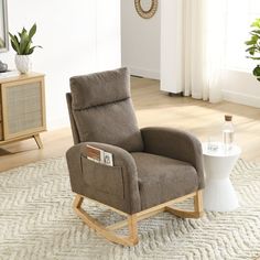 a rocking chair in a living room with a table and potted plant on the floor