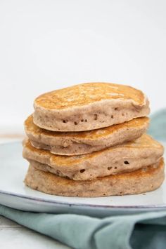 a stack of pancakes sitting on top of a white plate next to a blue towel