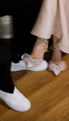 two people in white shoes standing next to each other on a wooden floor with their feet tied up