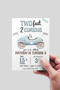 a person holding up a two fast 2 car birthday card