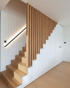 a wooden stair case next to a white wall