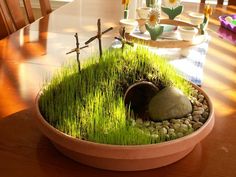 a potted plant sitting on top of a wooden table next to a cross and rocks