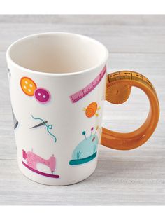 a coffee cup with scissors and sewing related items on the inside is sitting on a table