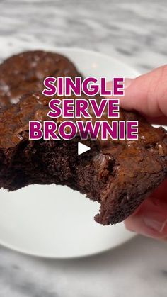 a hand holding a brownie on top of a white plate with the words single serve brownie