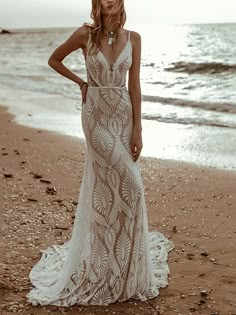 a woman standing on top of a beach next to the ocean wearing a white dress