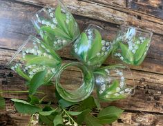 four glass vases with lily of the valley flowers in them sitting on a wooden table