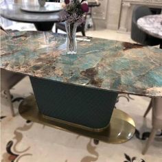 a table that has some flowers in it on top of a metal stand with other tables and chairs behind it