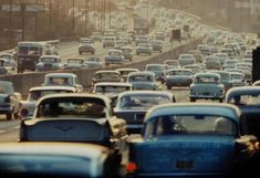 many cars are driving down the highway in heavy traffic, with palm trees behind them