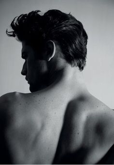 the back of a man's head and shoulders with no shirt on, in black and white