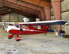 a small red and white plane in a hanger