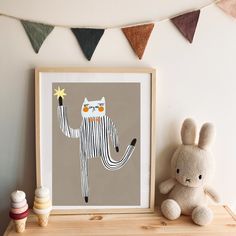 a stuffed animal sitting on top of a wooden shelf next to a framed art print