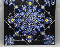 a blue and yellow painting on a black background with white border around the edges that has an intricate design in the middle