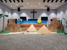 an empty room with cardboard pyramids and palm trees