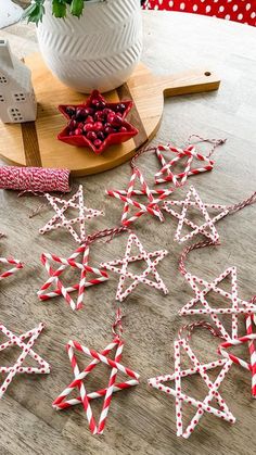 red and white paper stars on a wooden table next to a bowl of pomegranates