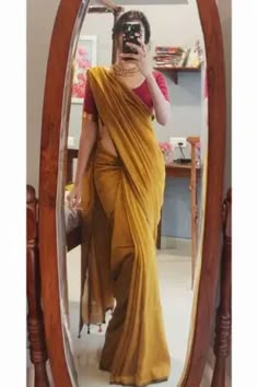 a woman in a sari taking a selfie with her cell phone while standing in front of a mirror