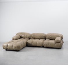 a large sectional couch with pillows on it in a room that is white and has no walls