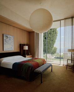 a bedroom with a large bed sitting next to a sliding glass door that leads outside