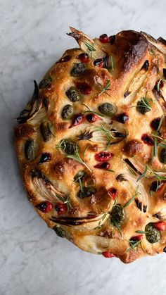 a pie with olives and other toppings sitting on top of a white table