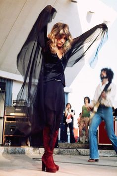 a woman in black dress and red boots dancing