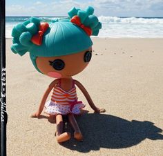 a doll sitting on the beach next to the ocean