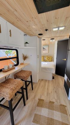 the interior of a tiny home with wood flooring and white walls, along with two stools