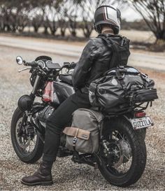 a person sitting on a motorcycle in the middle of the road wearing a leather jacket