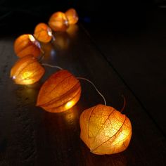 some lights that are on top of a wooden table and one is turned on to look like leaves