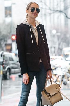 a woman is walking down the street with her hand in her pocket and holding a purse