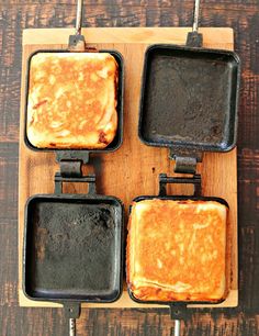 four square pans with food cooking in them on a cutting board next to utensils