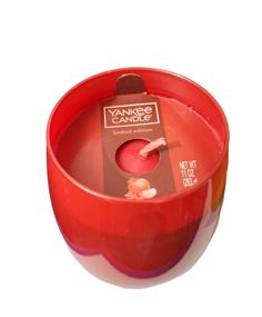 an orange and red candle holder sitting on top of a white surface with the label yankee candles