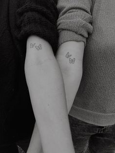 two people with tattoos on their arms holding each other's hands and one has a butterfly tattoo on it