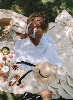 a woman laying on top of a blanket next to other items