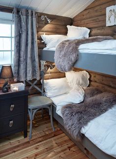 two bunk beds in a room with wooden walls and white sheets on the bedding