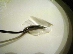 a spoon with cream on it sitting in a bowl