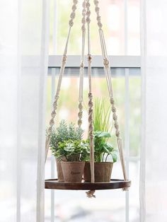 two potted plants are hanging from a window sill in front of a white curtain