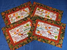 four placemats with autumn sayings on them sitting on a blue table cloth