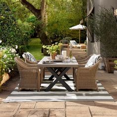 an outdoor dining area with wicker furniture and potted plants on the side walk