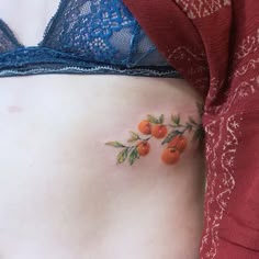 a woman's stomach with cherries and leaves tattooed on the side by her belly