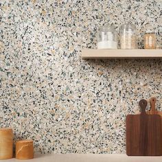 a kitchen counter topped with wooden utensils next to a wall covered in speckles