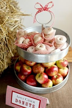 apples and donuts are stacked on top of each other in a metal bowl with a red ribbon