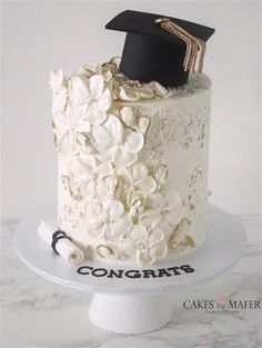 a cake with white flowers and a black graduation cap on top