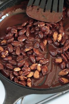 chocolate and almonds are being cooked in a skillet with a spatula on top