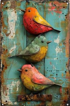 three colorful birds sitting on top of a blue wooden wall with rusted metal brackets