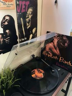 an old record player sitting on top of a table next to a plant and album