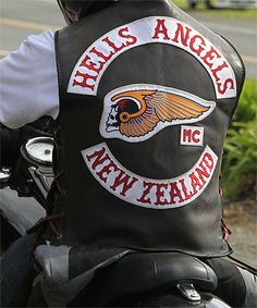 a man riding on the back of a motorcycle wearing a leather vest with angels and new zealand embroidered on it