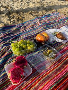 fruits and vegetables are sitting on a blanket at the beach