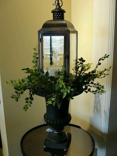 a lantern with greenery in it sitting on top of a table