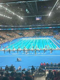 an olympic swimming pool is shown with people sitting on the bleachers watching it