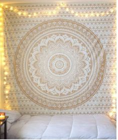 a bed with a large tapestry hanging on the wall next to a night stand and some lights